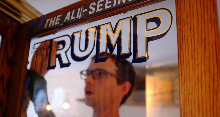 One of the makers reflected in the glass, placing the TRUMP lettering